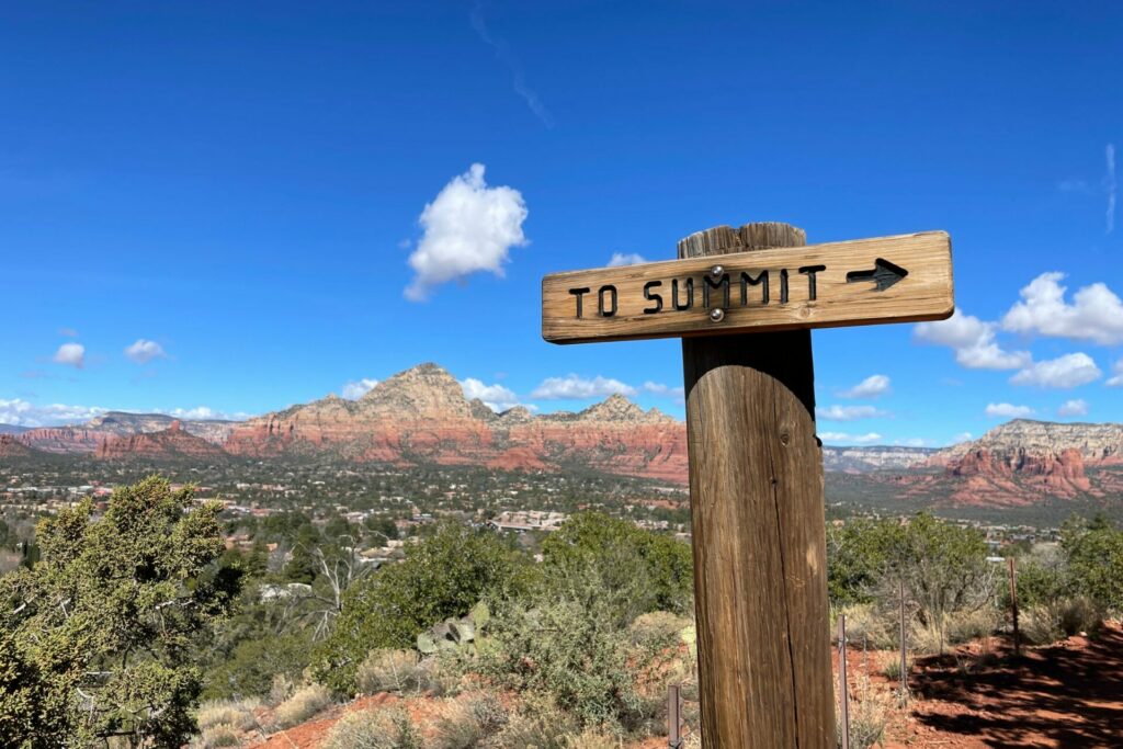 sedona mountains and deep blue sky in background with sign saying To Summit for a peaceful walk