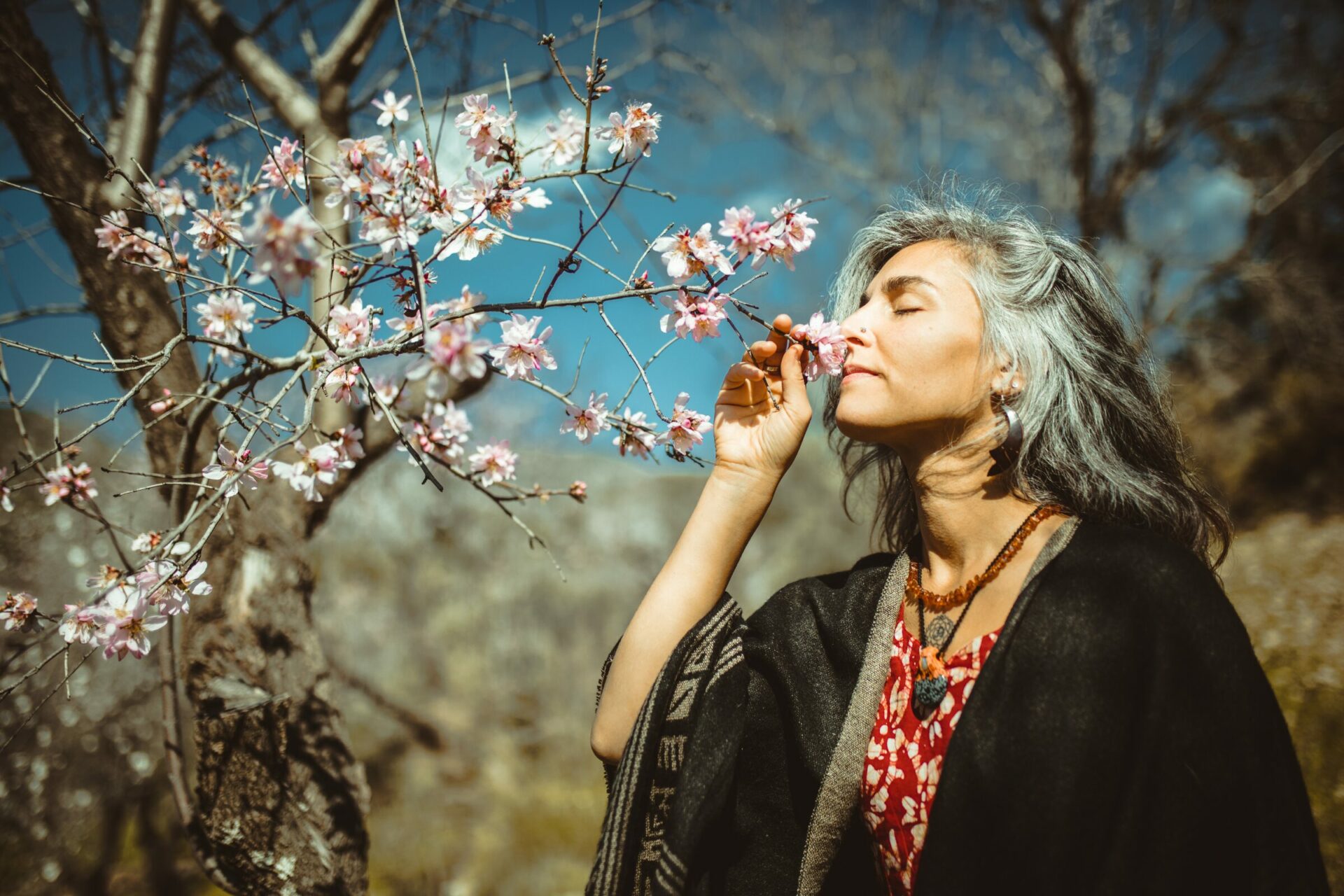 middle-aged woman smelling tree blossoms on a relaxing walk